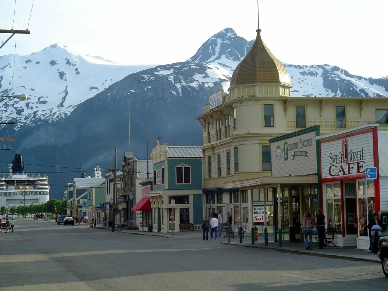 Colourful storefronts and boardwalk along Broadway in Skagway, Alaska, beneath snow-capped mountains